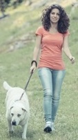 Chica paseando con su perro por el campo.