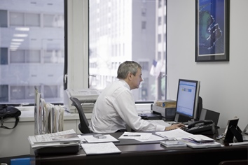 Señor de mediana edad en su despacho mirando la pantalla de su ordenador.