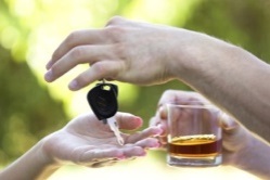 Primer plano de manos, donde una persona sujeta un vaso de whiskey y entrega las llaves del coche a otra persona